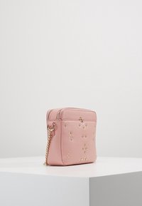 Borsa in pelle rosa con dettagli dorati, forma rettangolare, due scomparti con zip e borchie decorative sul davanti. Tracolla in catena attaccata.