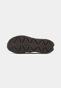 Suela de zapato de goma negra con una superficie texturizada que presenta patrones de diamantes y círculos, diseñada para ofrecer tracción y durabilidad.