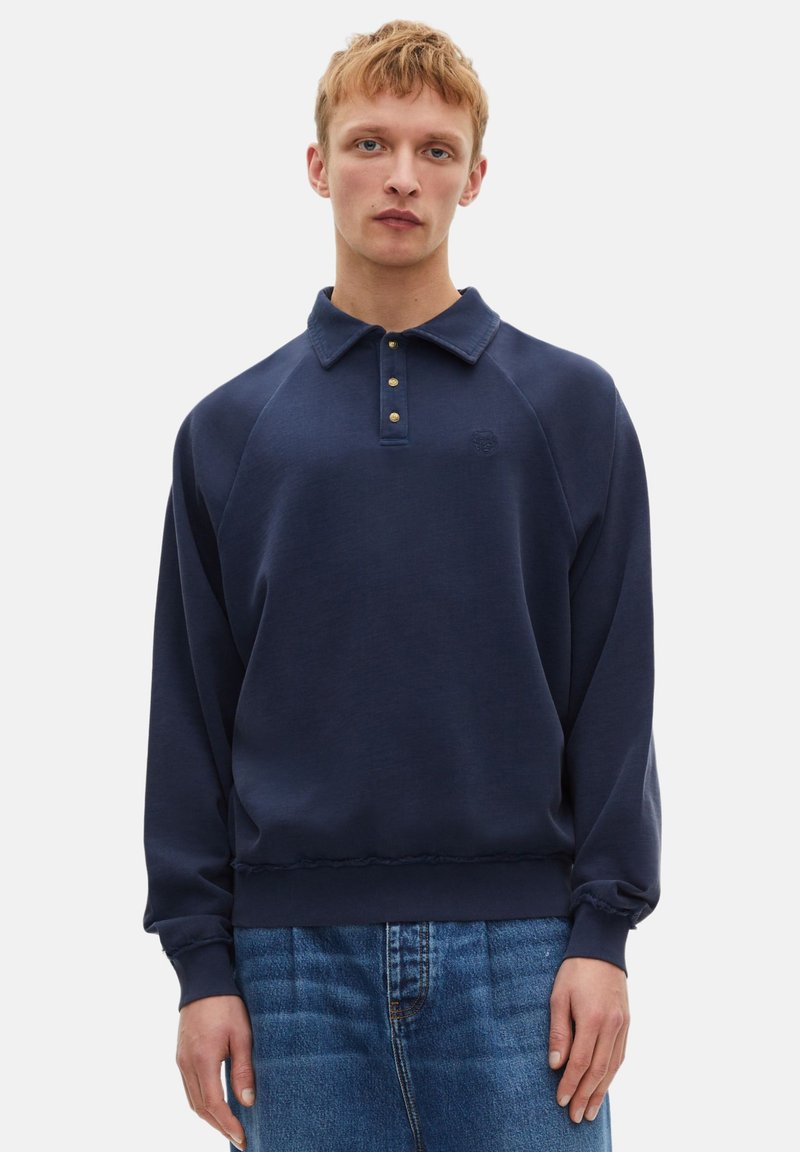 Felpa blu marinara con colletto polo, tre bottoni dorati e polsini a coste, realizzata in un tessuto testurizzato, con un logo sottile.