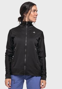 Schwarze Zip-Jacke mit hohem Kragen, seitlichen Reißverschlusstaschen und strukturiertem Stoff. Mit Logodetail auf der Brust und figurbetontem Design.