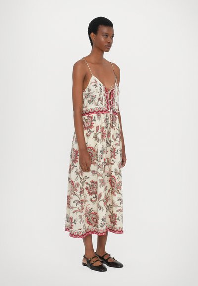 Robe à imprimé floral avec décolleté en V, bretelles réglables et taille cintrée. Présente des accents rouges et une longueur mi-mollet. Paire de chaussures noires.