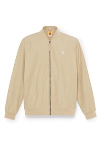 Chaqueta ligera color beige con cierre frontal, puños y dobladillo de canalé, dos bolsillos laterales y un pequeño logo en el lado izquierdo del pecho. Textura suave.