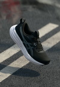 Čierna športová obuv s textúrovaným zvrškom, bielou medzipodrážkou a sivými doplnkami. Má šnurovanie a spevnenú špičku.