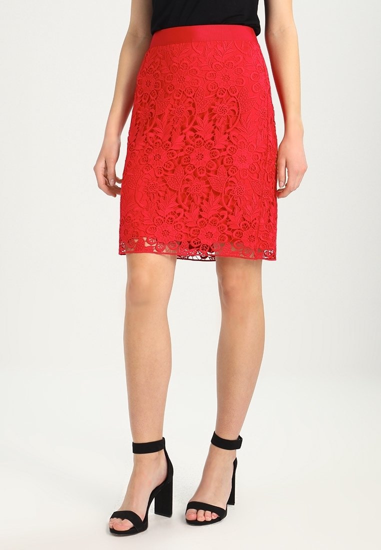 Jupe crayon en dentelle rouge à motif floral, avec un design texturé et une ceinture unie. Assortie à des escarpins noirs à bride cheville.