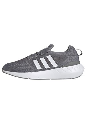Gray Adidas sneaker with white sole and three white stripes on knitted upper, viewed from the side on a white background.