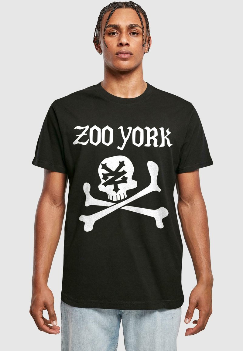 Juodas medvilnės marškinėliai su balta kaukolės ir kaulų grafika, virš kurios yra užrašas "ZOO YORK". Trumpomis rankovėmis, laisvas siluetas, apvalia iškirpte.