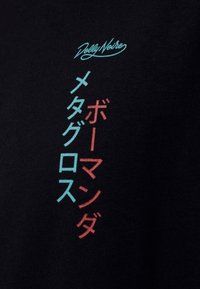 Schwarzes T-Shirt mit mehrfarbigem Text: hellblaue und rote japanische Schriftzeichen, sowie dem „Dolly Noire“-Logo in Schriftzug darüber. Aus Baumwollmaterial.