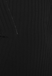 Tissu noir à côtes avec des rayures verticales, présentant un subtil détail de fermeture éclair sur un côté. Le matériau semble texturé et élastique.