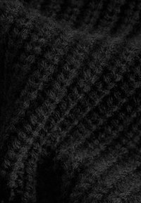 Tissu tricoté noir avec une texture douce et duveteuse, présentant un motif à côtes qui ajoute de la profondeur et de l'intérêt visuel.