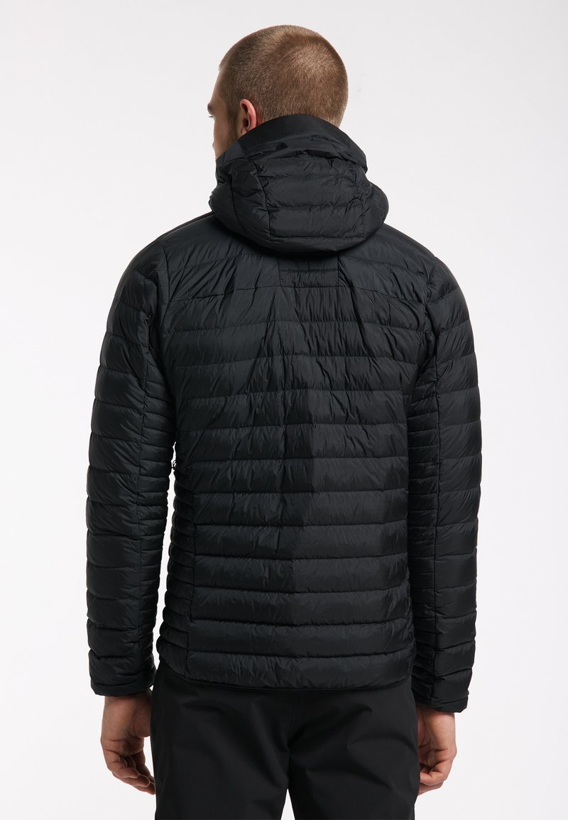 Chaqueta de plumas negra con capucha, con un diseño acolchado horizontal, material ligero y silueta ajustada, vista desde la espalda.