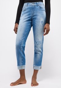 Hellblaue Denim-Jeans mit hoher Taille, abgetragenen Details an den Beinen und umgeschlagenen Säumen. Verfügt über fünf Taschen und einen silbernen Knopfverschluss.