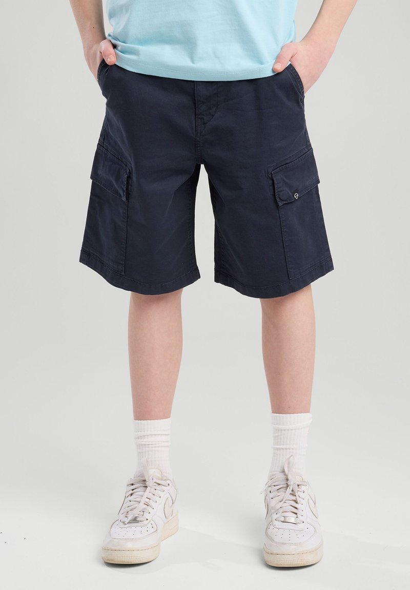 Pantaloni cargo navy con due tasche laterali, realizzati in cotone. Presentano una vestibilità comoda e un orlo cucito. Abbinati a sneakers bianche e calzini.