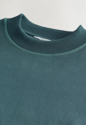 Türkiser Sweatshirt mit geripptem Rundhalsausschnitt und strukturiertem Stoff. Besitzt flache Nähte und ein Etikett im Kragen.