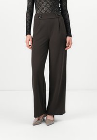 Pantalons larges marron en tissu lisse avec taille haute, présentant deux boutons à l'avant et des plis pour une touche supplémentaire.