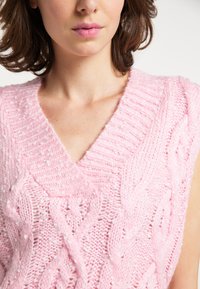 Roze gebreide mouwloze trui met V-hals, met gestructureerde kabelpatronen en een zachte, fluweelachtige feel.