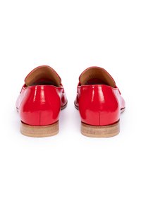 Mocassins en cuir laqué rouge avec un petit talon en bois et un bout arrondi, présentant une texture lisse et brillante ainsi qu'un design sans lacets.