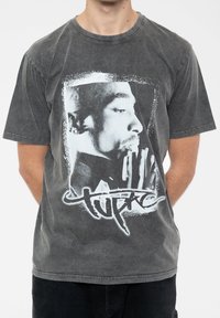 Gray cotton T-shirt featuring a front graphic of a black-and-white portrait with the name "Tupac" below, set against a distressed background.