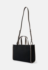 Bolso tote de lona negra con acentos de cuero gris, que cuenta con dos asas superiores y una correa acolchada desmontable. Forma rectangular, textura suave.