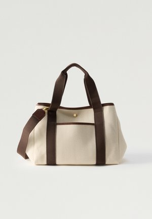 Beige Leinentasche mit dunkelbraunen Griffen, Besatz, Vordertasche und verstellbarem Schultergurt, vor weißem Hintergrund.