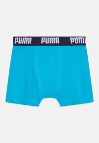 Tirkizne bokserice s mornarskom elastičnom trakom koja sadrži bijeli "PUMA" logo. Glatka tekstura i uski kroj, dizajnirano za udobnost.