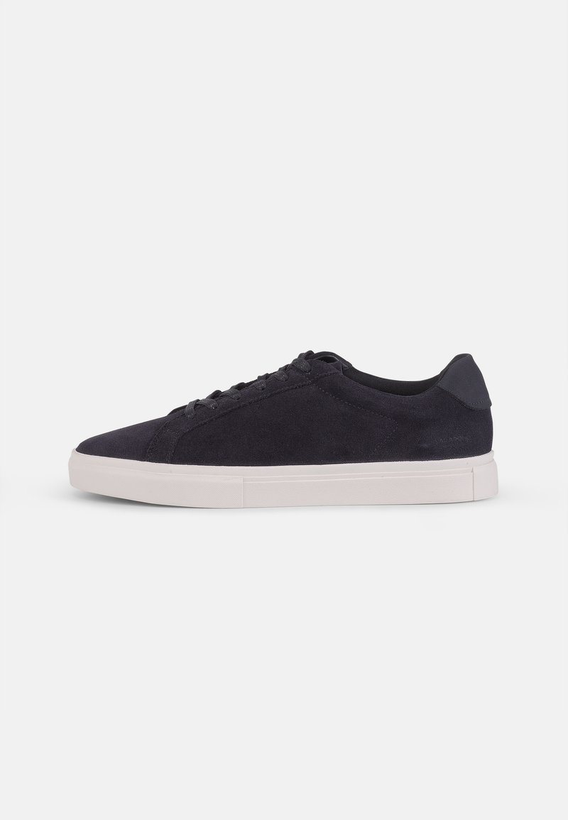 Navy suede sneaker with white rubber sole, rounded toe, lace-up closure, and contrasting heel accent, featuring a smooth texture.
