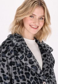 Cappotto in pelliccia sintetica a stampa leopardata grigia con colletto a scialle, chiusura a bottoni e texture morbida, caratterizzato da un leggero lucido e una vestibilità comoda.