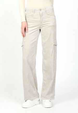 Helle beigefarbene Corduroy-Cargohosen mit weitem Bein, Seitentaschen und subtiler Textur. Getragen mit weißen Sneakers.