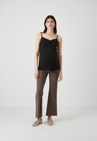 Black lace-trimmed camisole paired with brown ribbed, flared trousers and woven slip-on shoes in a light-toned setting.