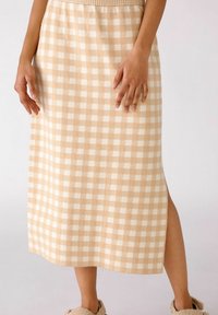 Falda midi de cuadros beige con cuadrados blancos, que presenta una abertura lateral y una cinturilla texturizada. Tejido suave.