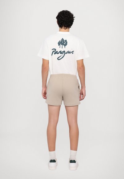 Weißes Baumwoll-T-Shirt mit einem grafischen Druck auf der Rückseite, kombiniert mit beigen Shorts. Die Shorts verfügen über einen elastischen Bund und seitliche Taschen.