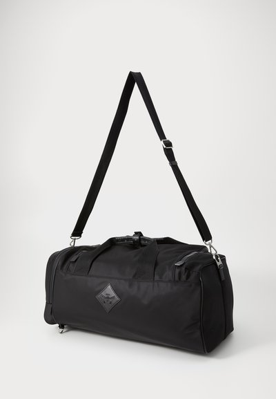Black duffel bag made of nylon, featuring sturdy handles, an adjustable shoulder strap, and a diamond-shaped logo accent. Smooth texture.