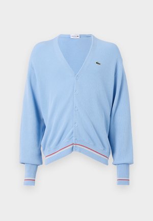Lichtblauwe cardigan met een V-hals, knoopsluiting en ribgebreide mouwen. Opvallende rode en witte streepaccenten aan de zoom en mouwen. Lacoste-logo aanwezig.