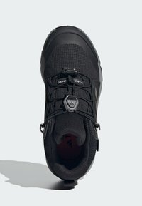 Black outdoor shoe with a textured synthetic upper, lace closure system, padded collar, and contrast red inner lining. Durable rubber outsole.
