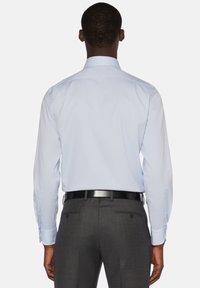 Ljusblå skjorta med klassisk krage, långa ärmar och knappar. Kombinerad med mörkgrå skräddarsydda byxor och svart bälte.