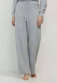 Helle graue, weit geschnittene Loungehosen aus weichem, strukturiertem Stoff mit elastischem Bund und verstellbarem Kordelzug. Keine sichtbaren Muster.