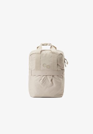 Beige backpack with two top handles, padded body, and two round accents. Paired with black long-sleeve shirt and light, loose-fitting trousers.