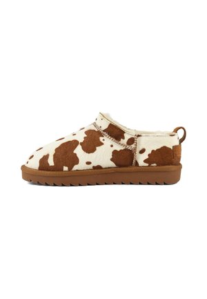 Chausson bas avec dessus en fausse fourrure imprimé vache marron et blanc, doublure douce et semelle en caoutchouc marron avec languette au talon.