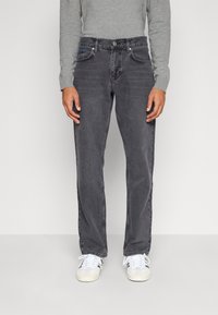 Jeans da uomo in denim grigio con taglio dritto, design a cinque tasche e dettagli di sbiaditura sottili. Abbinati a sneaker bianche e una maglietta grigia a maniche lunghe.