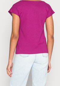 Fuchsian t-shirt i bomull med korta ärmar och avslappnad passform, tillsammans med ljusblå denimjeans. Enkelt design, inga synliga mönster eller accenter.