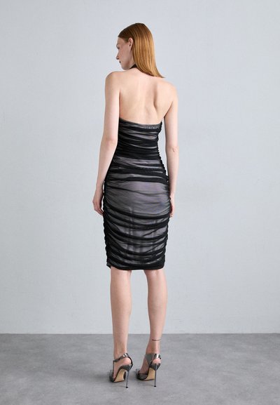 Robe froncée noire avec un tissu transparent, design sans manches, longueur mi-mollet et silhouette ajustée. Accentuée d'un léger éclat.