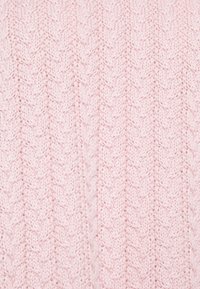 Svetle růžová pletenina se strukturovaným vzorem cik-cak, který má vyvýšené stehy a jemný, pohodlný vzhled.