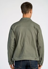 Groene katoenen jas met een ontspannen pasvorm, voorzien van een puntige kraag, lange mouwen en knoopaccenten bij de manchetten. Achteraanzicht getoond.