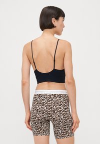 Svart crop-top med spagettistropper, kombinert med leopardmønstrede sykkelshorts, som har elastisk midje med hvit merkevare og en glatt tekstur.