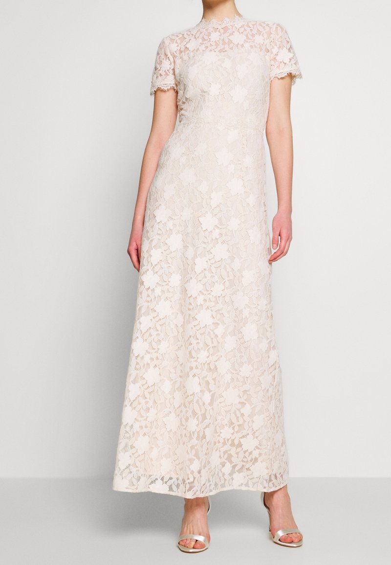 Robe de soirée en dentelle beige clair, dotée d'un corsage ajusté, de manches courtes et d'une jupe longue ornée de motifs floraux.