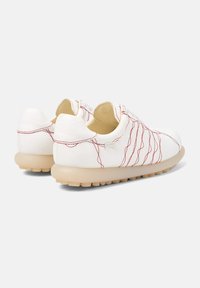 Zapatos blancos con detalle de costura roja, forma redondeada, suela beige ligera y superficie texturizada. Marca mínima en el talón.
