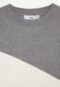 Gray sweater featuring a textured knit design with a contrasting white diagonal panel. Round neckline and ribbed cuffs.