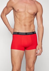 Boxer-briefs rouges en tissu doux, avec une taille noire portant le logo "PUMA". Le design comprend une coupe ajustée et une couverture de jambe courte.
