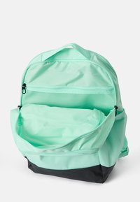 Mochila verde menta con base negra, cuenta con compartimentos dobles, bolsillos de malla y cierres de cremallera para un almacenamiento seguro.