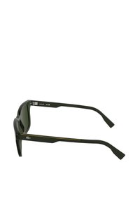 Czarne plastikowe okulary przeciwsłoneczne z zielonymi soczewkami. Smukły, kanciasty design z żółtym akcentem na zausznikach i logo po boku.