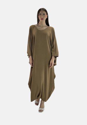 Brun, oversized kaftankjole med løs pasform, lange ærmer og et struktureret stof. Sammen med lyse åbne sko.
